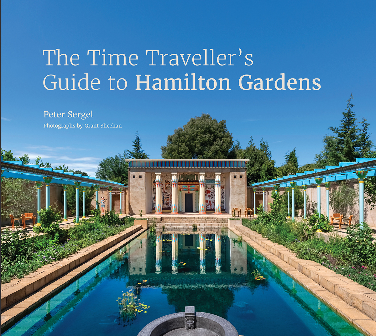 A book cover with the text The Time Traveller's Guide to Hamilton Gardens, and the names Peter Sergel, and Grant Sheehan. The text is over an image of a faux Roman Bath with a large pool surrounded by columns.